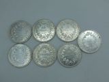 six types différents de pièces d'argent posées sur une table