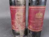 two bottles of red wine sitting next to each other on a table