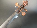 an old violin sitting on top of a table next to a black table