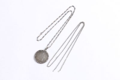 trois colliers en argent posés sur une surface blanche, avec une chaîne
