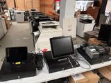 de nombreux ordinateurs portables et écrans posés sur une table dans un entrepôt