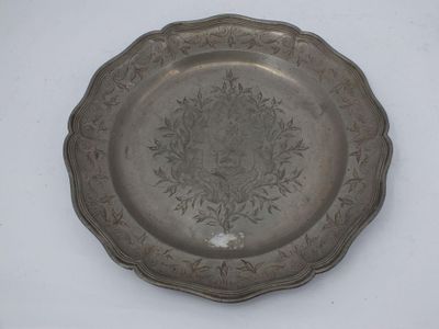 une plaque d'argent ornée d'un motif sur une surface blanche