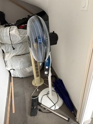un ventilateur posé par terre à côté d'une pile de sacs