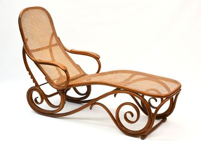 une photo d'une chaise longue en osier avec un repose-pieds