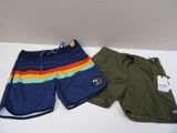 two men ' s swim trunks and shorts are on a white table