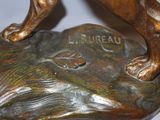 bronze statue of a dog standing on a rock with its paw on it ' s head