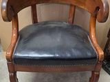 a black leather chair with a wooden frame and black leather seat