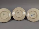 three white plates with designs on them sitting on a gray surface