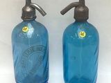 une paire de bouteilles en verre bleu surmontées de bouchons métalliques