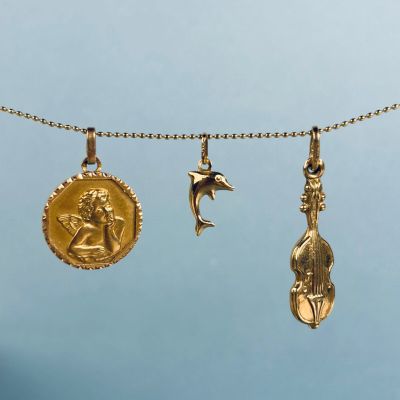 trois pendentifs en or suspendus à une cordelette, représentant un oiseau et une étoile