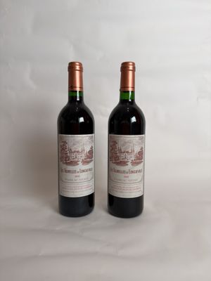 two bottles of red wine sitting next to each other on a white surface