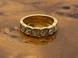 bague en or jaune sertie de diamants posée sur une surface en bois