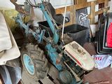 a small blue tractor sitting next to a television