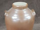 a brown vase sitting next to a piece of cake