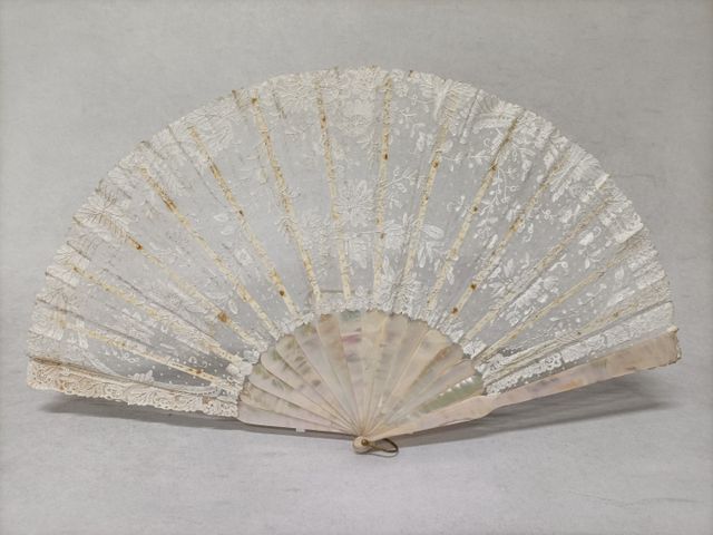 Grand éventail, la feuille en dentelle à décor de fleurs variées.
