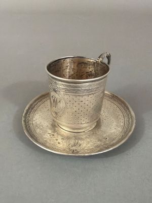 une tasse et une soucoupe en argent posées sur une soucoupe