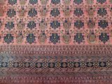 an image of a pink rug with blue and yellow designs on it