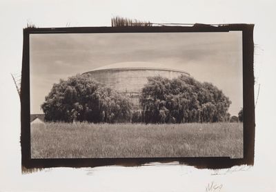 an old photo of a large building in a field with trees