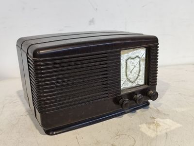 une vieille radio noire posée sur une table près d'un mur blanc