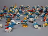 toy figurines of the smurfs are arranged on a gray surface