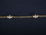 a gold chain bracelet with silver beads on a black background