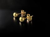a pair of gold stud earrings on a black surface