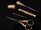 three pairs of gold scissors and a pair of silver scissors on a black surface