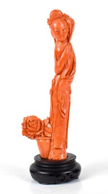 une statue orange représentant une femme tenant un pot de fleurs, posée sur un socle noir