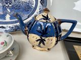 a blue and white teapot sitting on a table next to a plate