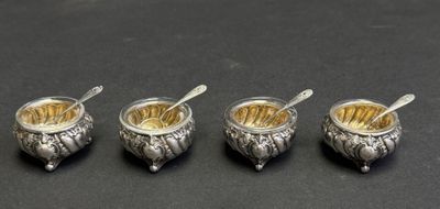 four silverplated bowls with spoons and spoons on a black surface