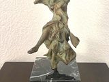 statue d'une femme posée sur un socle en marbre, elle-même posée sur une table en bois