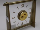 a small gold clock with numbers on it on a white surface