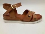 a pair of tan sandals with gold buckles and a white sole