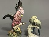 two figurines of birds that are sitting on a branch