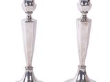 paire de bougeoirs plaqués argent sur un socle, sur fond blanc