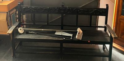 un banc noir sur lequel repose une batte de baseball, dans une pièce