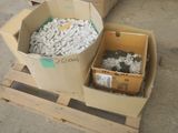 deux cartons de cailloux blancs sur une palette, à côté d'un carton de cailloux noirs