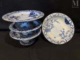 three blue and white plates and a bowl on a black table