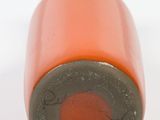 an orange bottle with a black cap sitting on top of a white surface