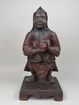 une vieille statue en bois d'un homme avec un chapeau sur la tête