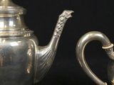 two silver teapots sitting next to each other on a table