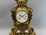 une horloge en or surmontée d'un oiseau