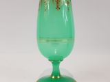 green glass goblet with gold decoration on base on white background