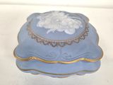 a blue box with a gold trim and a white flower on it