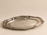une assiette en argent posée sur une table, sur fond blanc