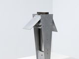 a metal sculpture of a bird on a stand