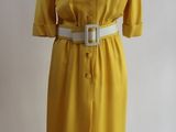 robe jaune posée sur un présentoir à mannequin, avec une ceinture blanche
