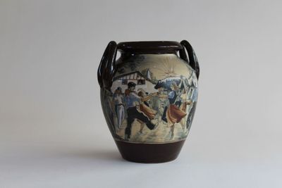 a vase with a painting on it sitting on a table