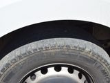 a cat sitting on the tire of a white truck