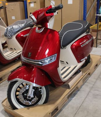 un scooter rouge et blanc posé sur une palette dans un entrepôt